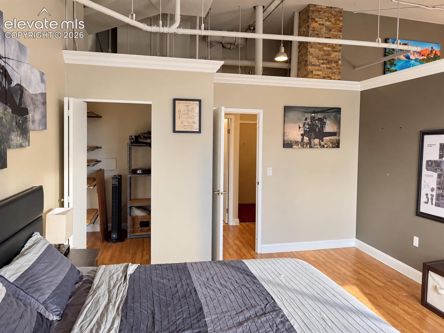 Exposed ceiling pipes, wood-finish flooring, and a stone-clad column define this interior space