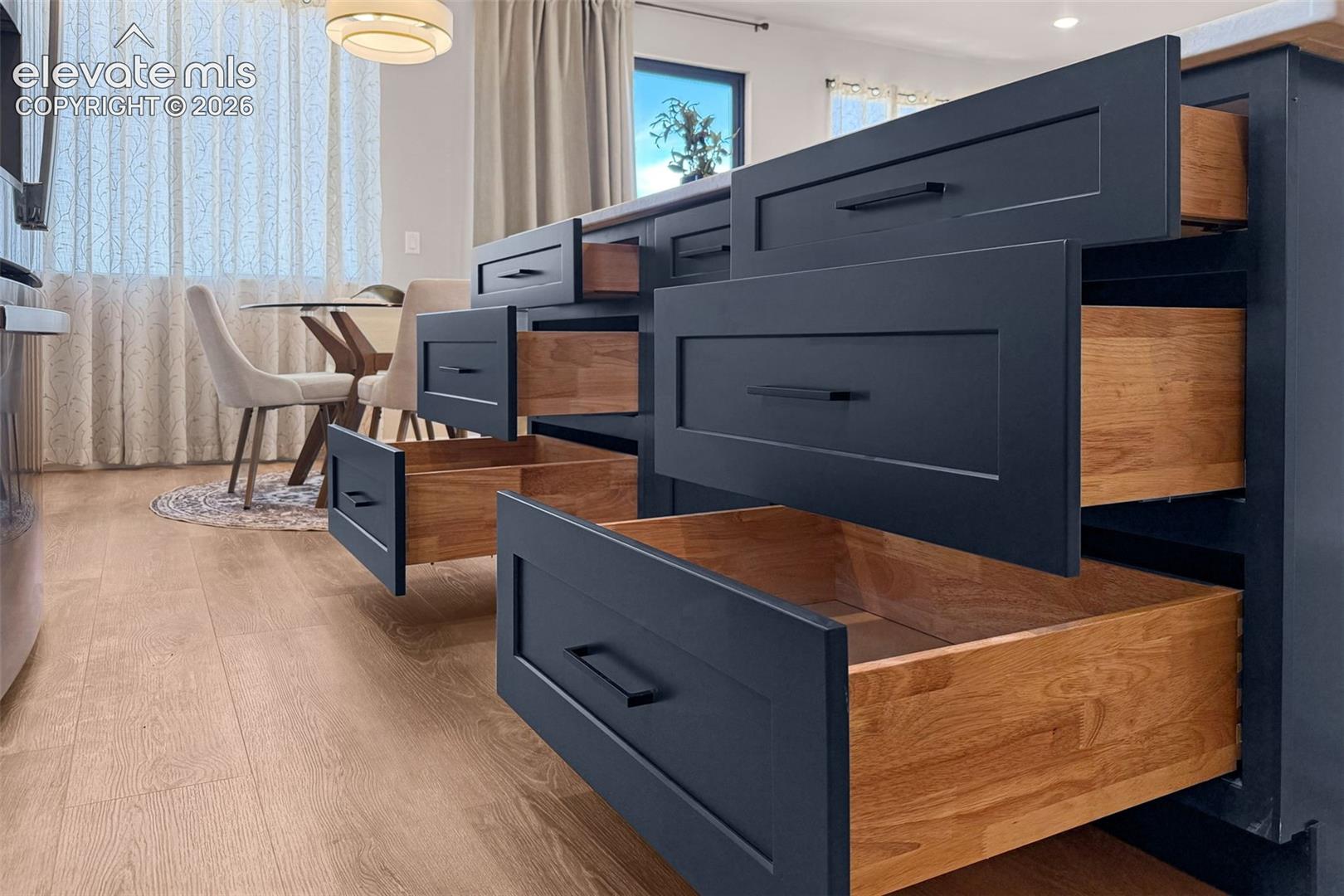 Kitchen island featuring dark blue cabinetry with flat-panel drawer fronts and black hardware
