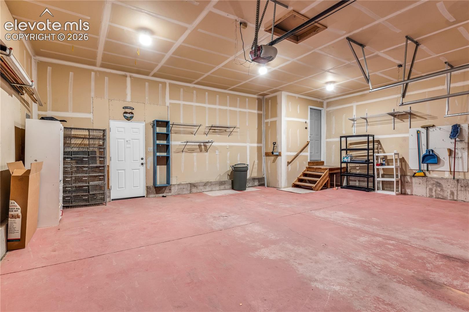 Spacious garage featuring a finished ceiling, multiple light fixtures, and a side access door