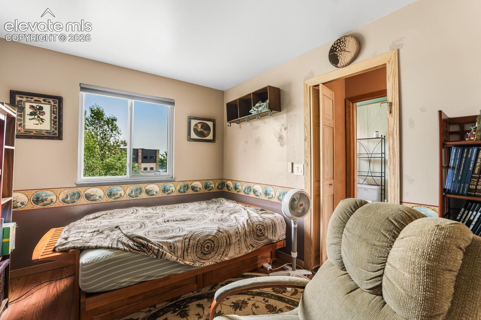 Room featuring a single window, two-tone walls with a decorative border, a wood-finish platform, and built-in shelving