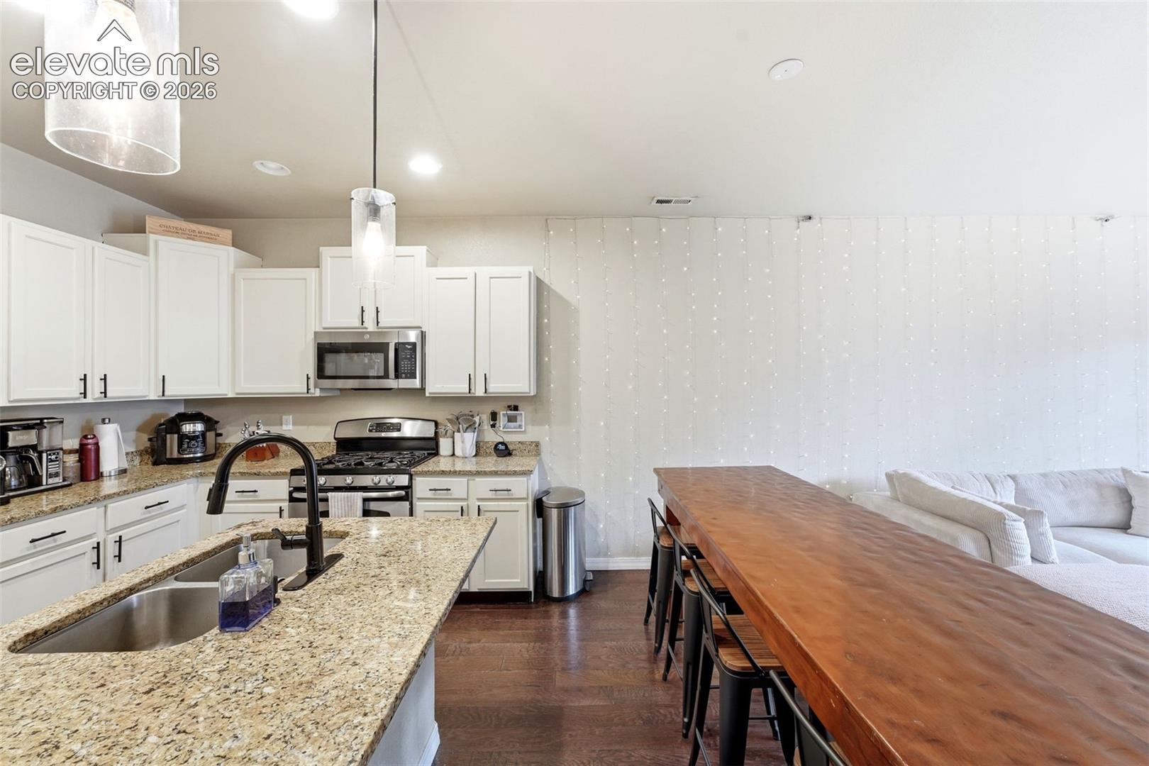 Kitchen featuring granite countertops, a stainless steel gas range, microwave, and a double-basin undermount sink with a matte black faucet