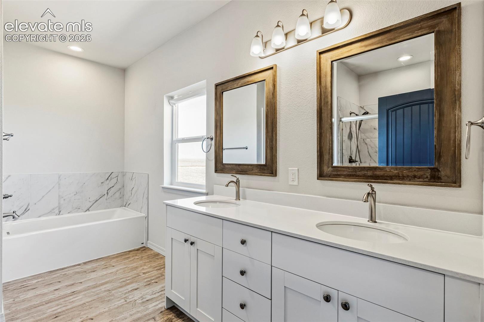 Dual vanity featuring white cabinetry with dark hardware, undermount sinks, and light-colored countertops