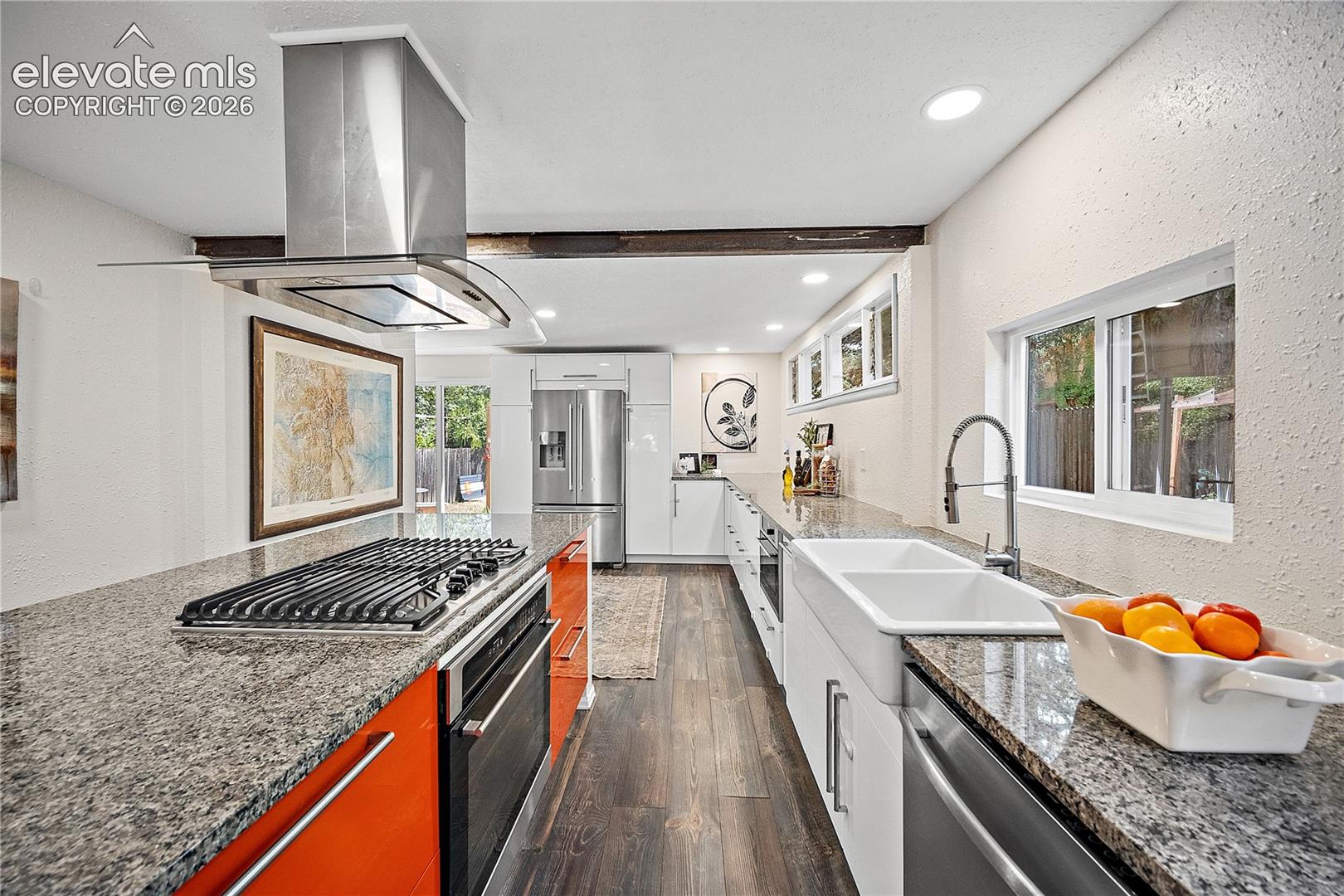 Modern kitchen featuring granite countertops, wood-finish flooring, and a stainless steel island range hood