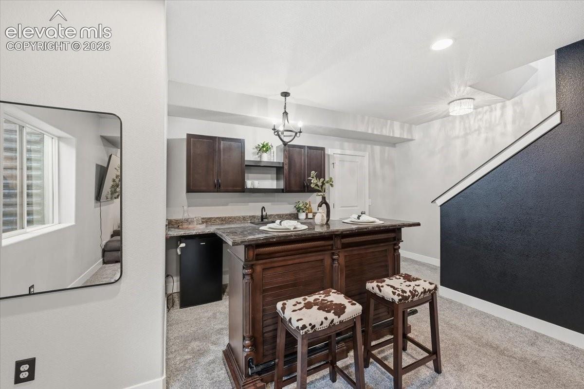 Built-in wet bar with wood cabinetry, dark countertops, and a beverage refrigerator