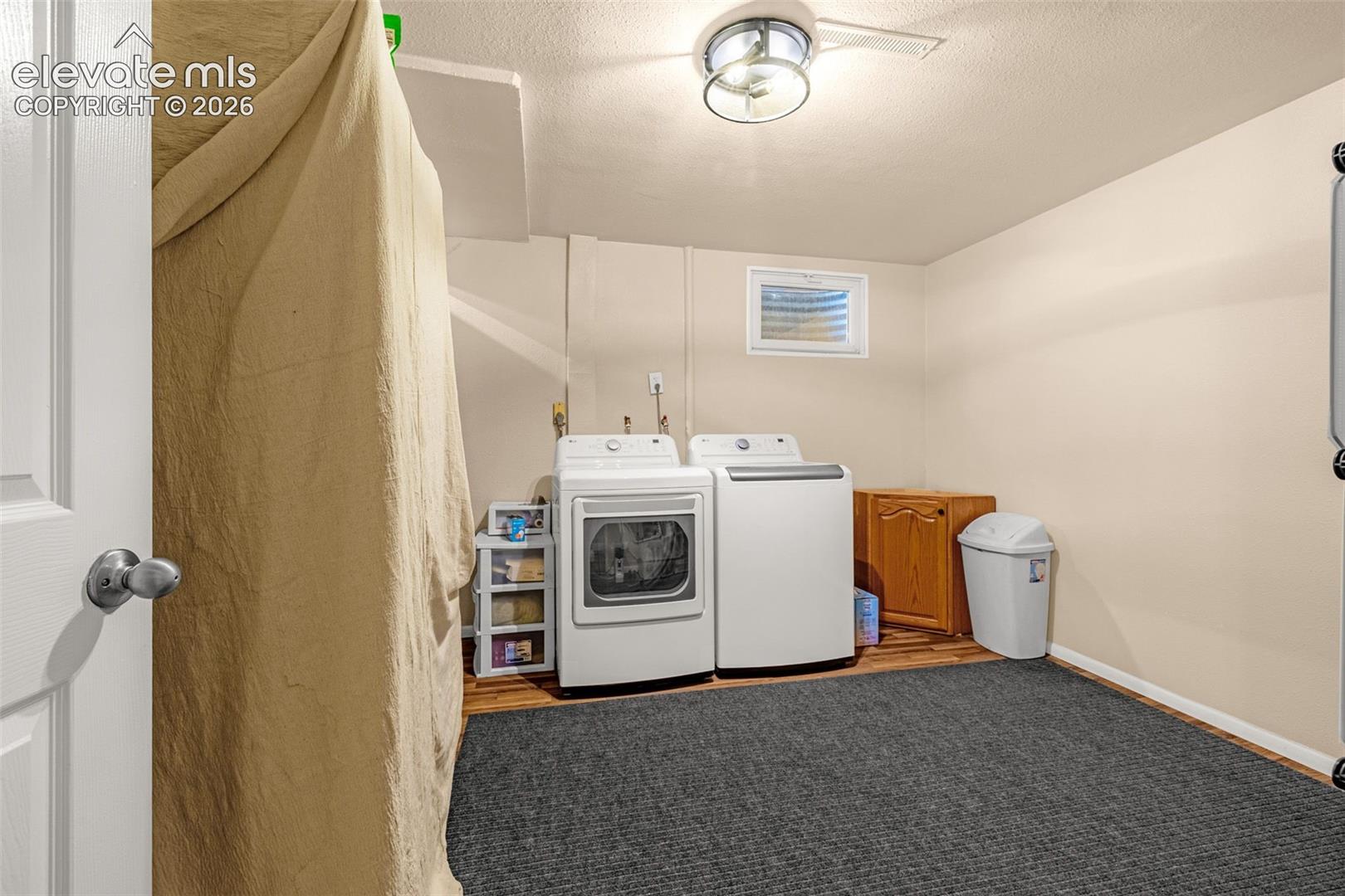 Laundry area with laminate wood-finish flooring and a recessed window