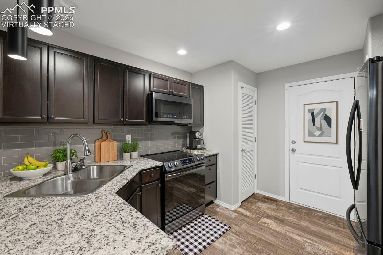 Kitchen featuring stainless steel appliances, dark brown cabinetry, recessed lighting, granite countertops, and baseboards. This photo is virtually staged.