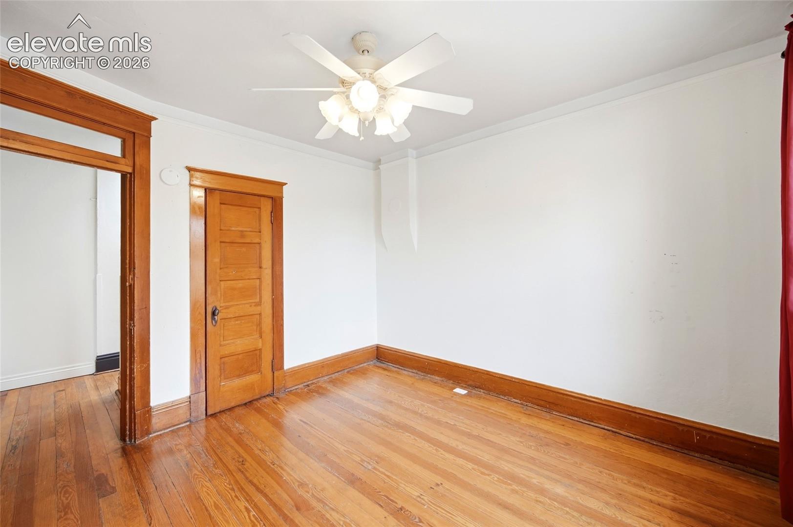 Wood-finish flooring, natural wood-tone door and trim, and ceiling fan with integrated lighting