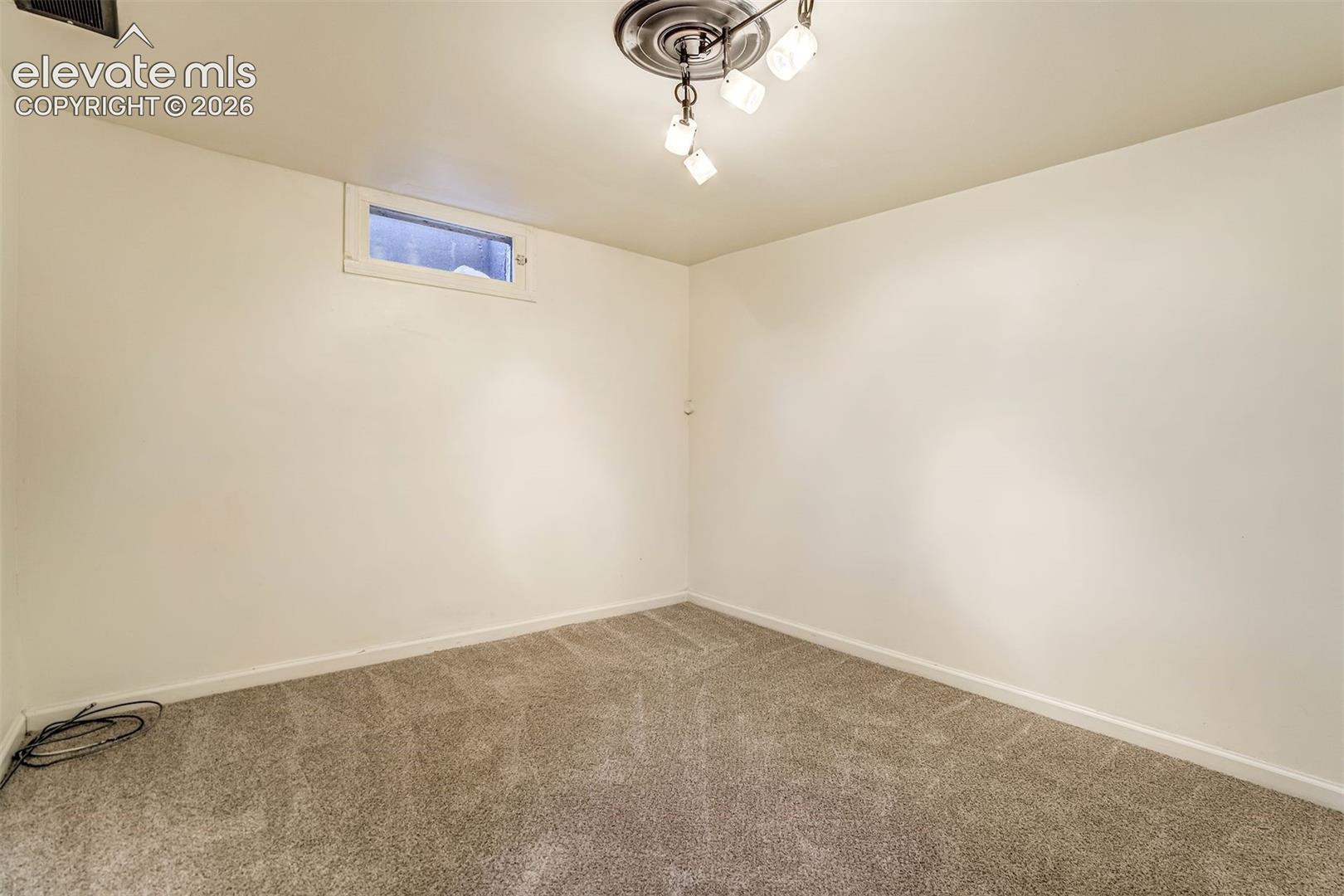 Neutral-toned carpeting, high-gloss finished walls, horizontal rectangular window, and a three-light ceiling fixture with a decorative ceiling medallion