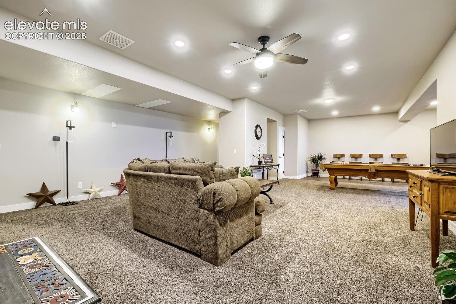 Spacious entertainment area with recessed lighting, ceiling fan, and carpeted flooring