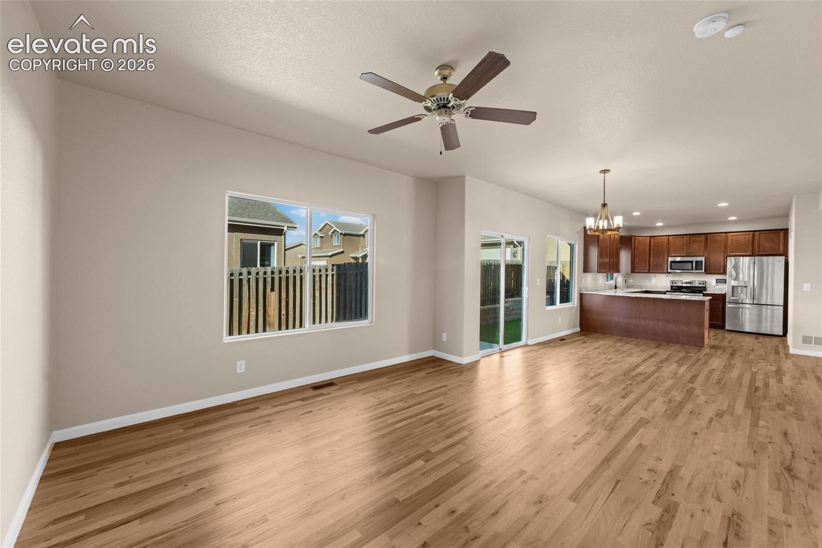 Open floor plan featuring wood-finish flooring, recessed lighting, a ceiling fan, and a kitchen equipped with wooden cabinetry and stainless steel appliances