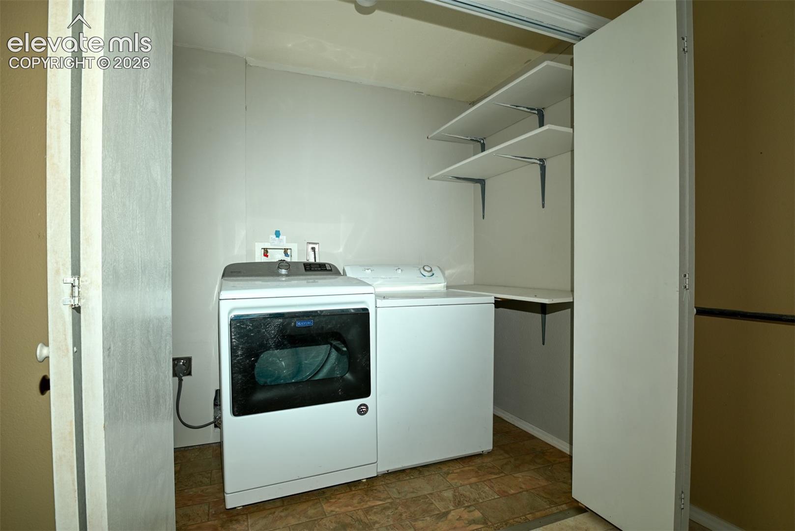 Dedicated laundry area with durable flooring, built-in shelving, and a folding surface