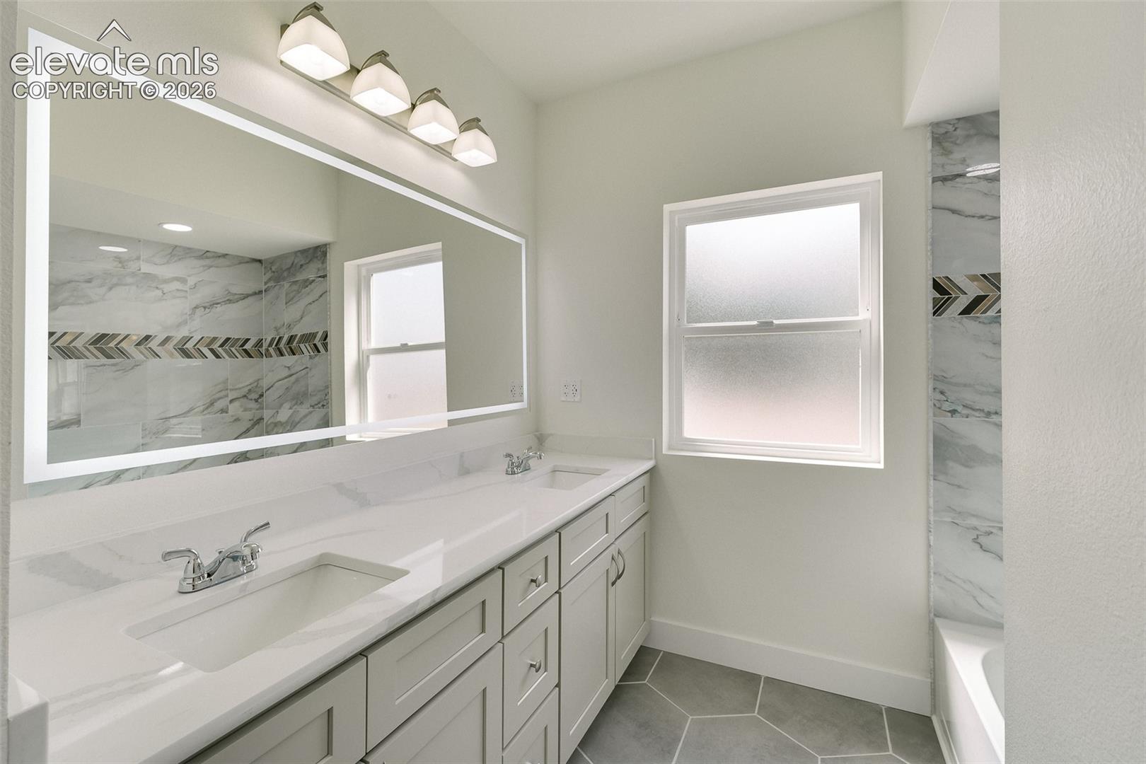 Upper Level Full Bathroom with dual sink vanity, quartz countertop, illuminated and fog resistance mirror, and tiled tub/shower.