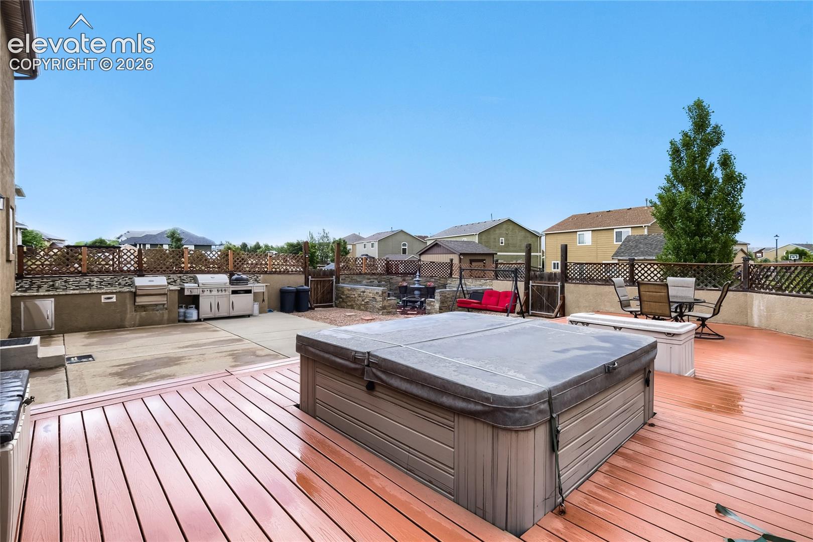 Expansive outdoor living area featuring outdoor kitchen, a large, composite wood deck, built-in hot tub, and expansive concrete patio. Rear storage shed is a plus,