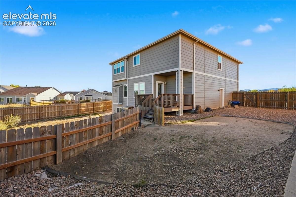 Two-story exterior featuring lap siding, a raised wood deck with railing, and a fenced perimeter