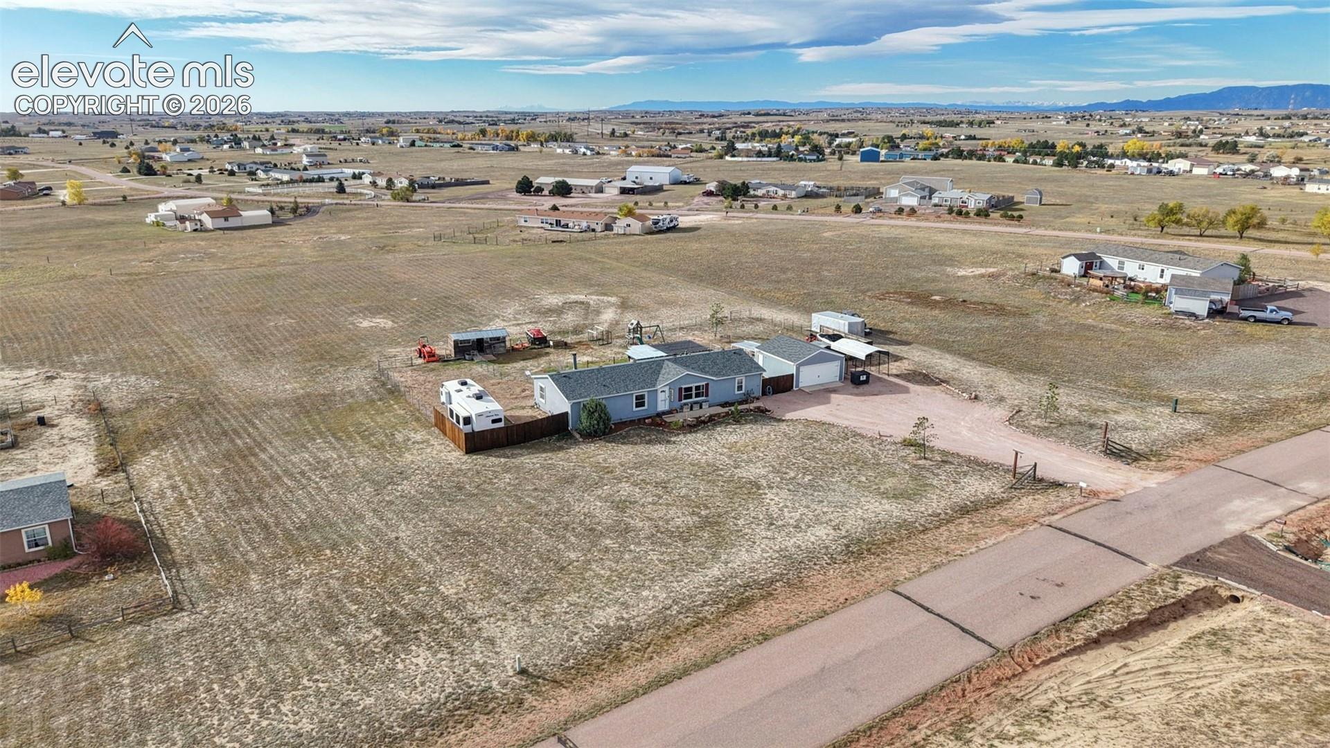 Expansive acreage featuring a detached garage, asphalt driveway, wood fencing, and distant mountain topography