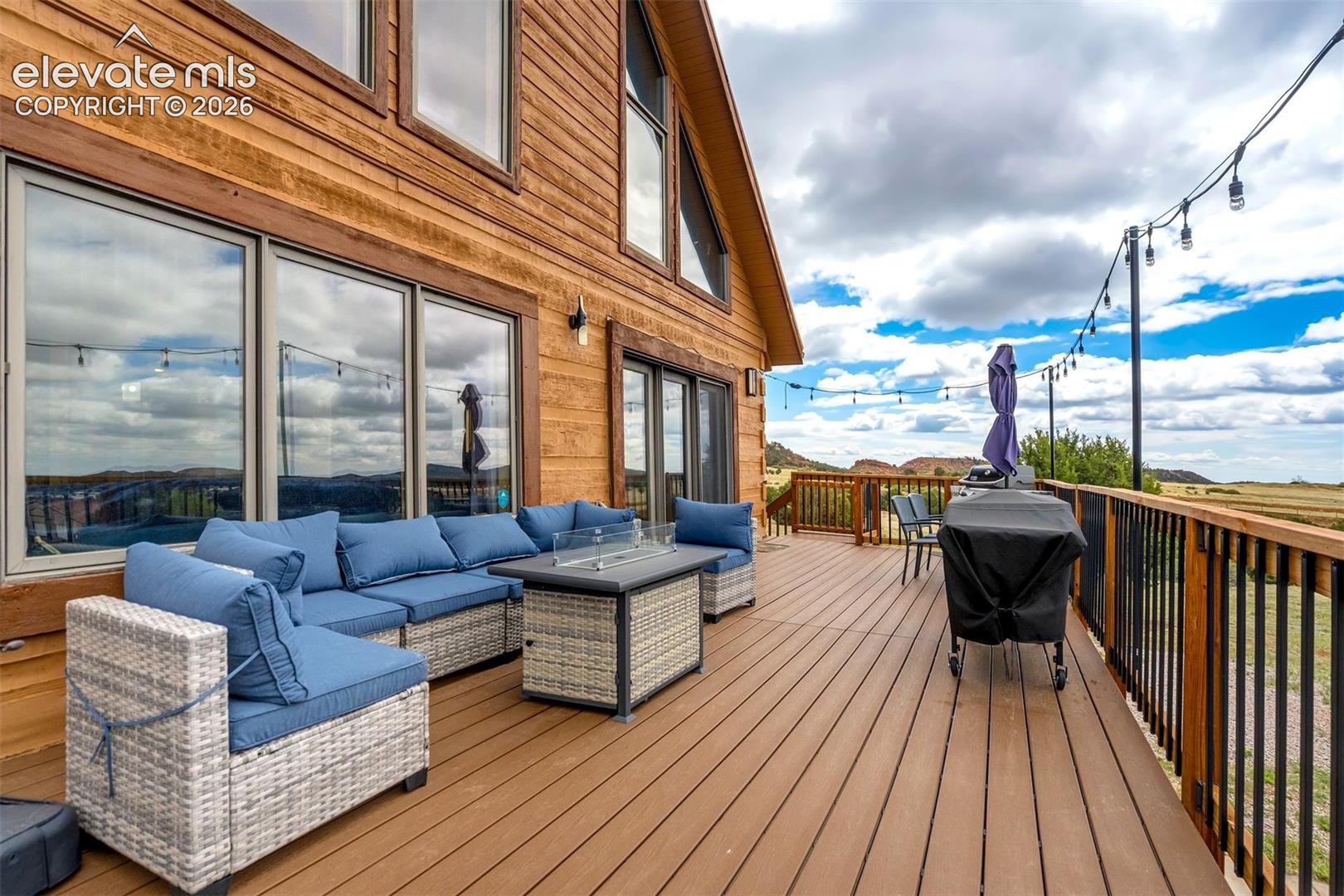 Spacious outdoor deck featuring wood-finish flooring, black metal railings, and a wood-paneled exterior