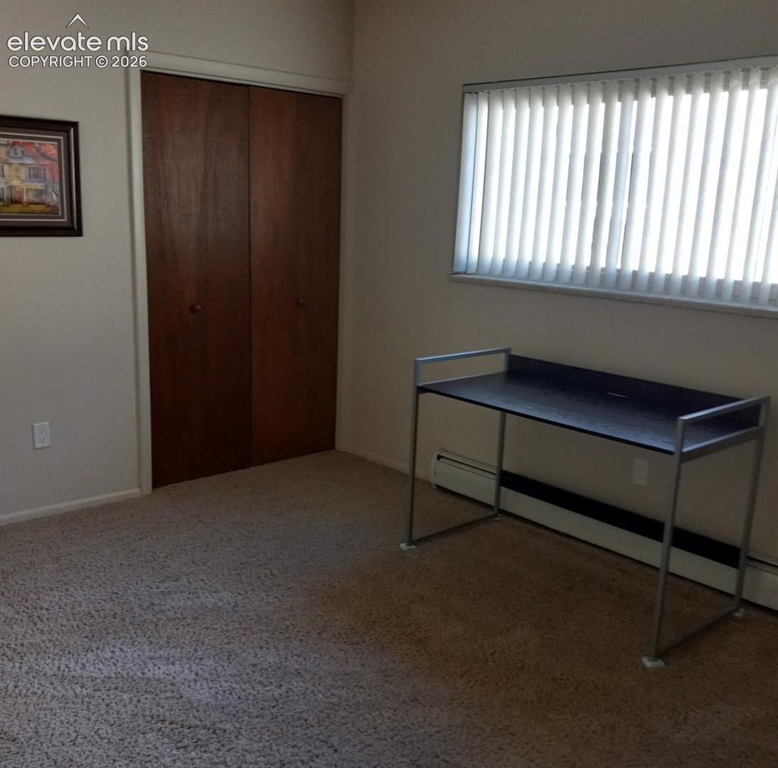 Room featuring neutral wall-to-wall carpeting, wood-finish bi-fold closet doors, and horizontal window blinds