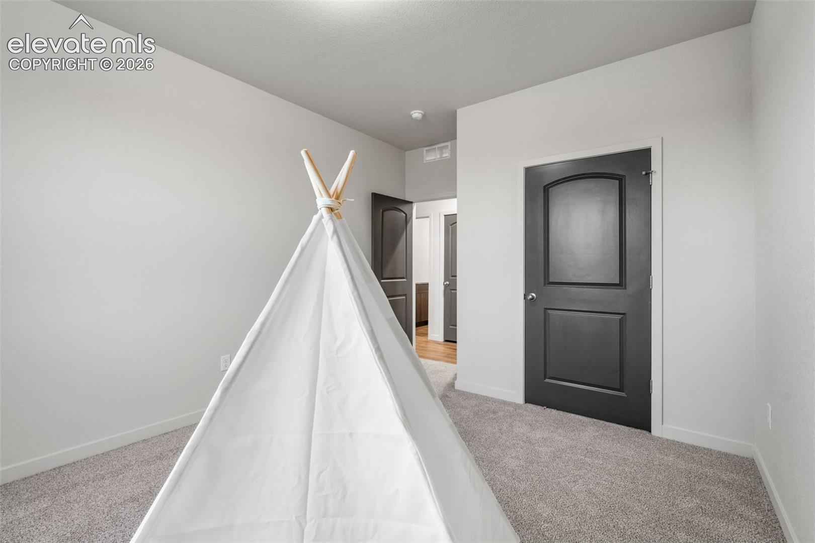Neutral wall palette with carpeted flooring and dark-finish arch-top interior doors