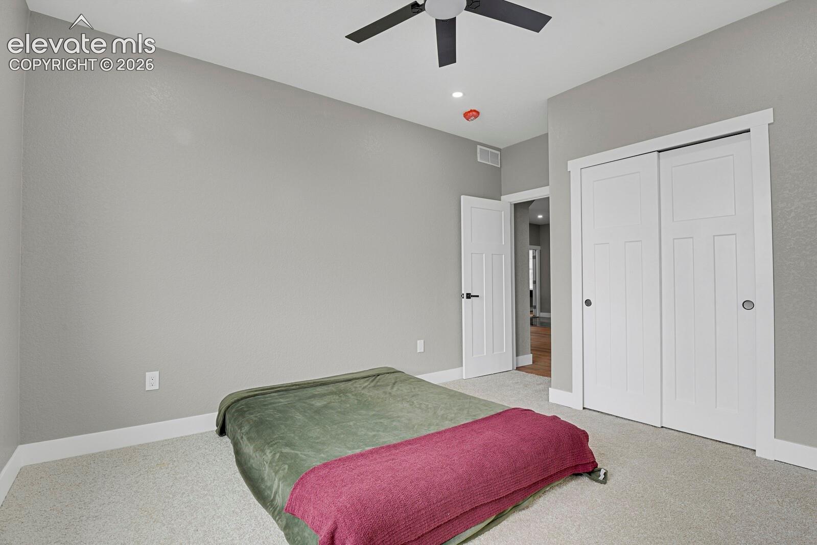 Neutral-toned room featuring neutral carpeting, a ceiling fan, and white paneled interior doors with matte black hardware