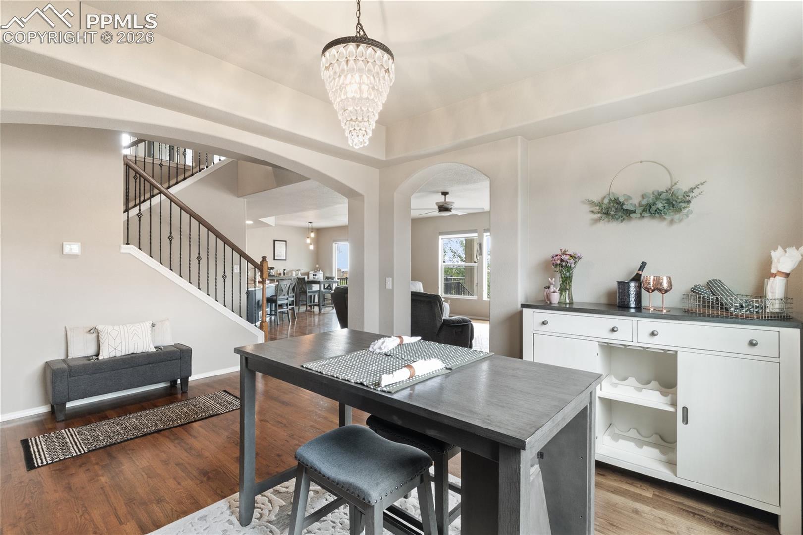 Dining room featuring arched walkways, suspended lighting, a raised ceiling, wood finished floors, and ceiling fan