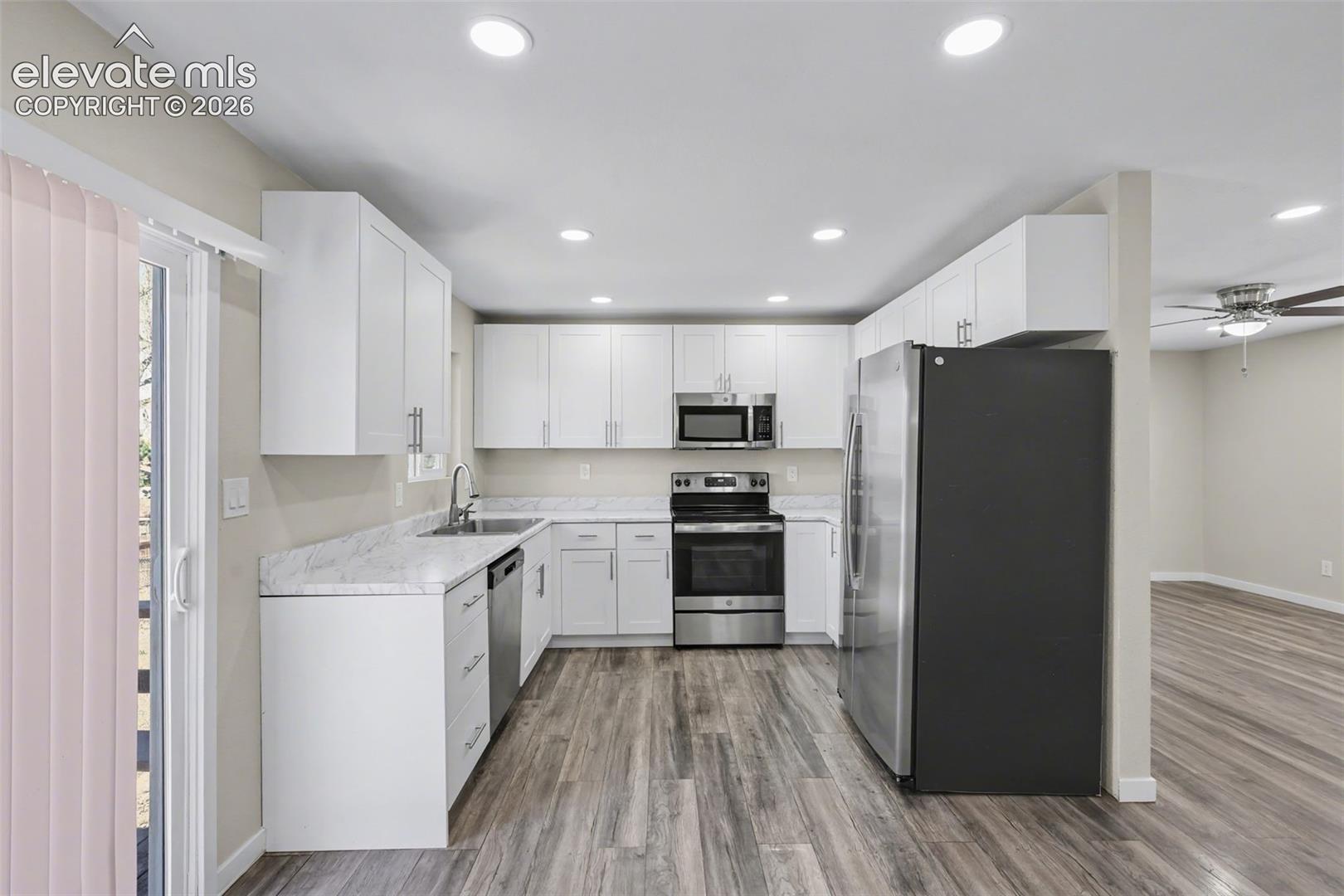 Kitchen featuring white cabinetry, stone-finish countertops, stainless steel appliances, recessed lighting, and wood-finish flooring