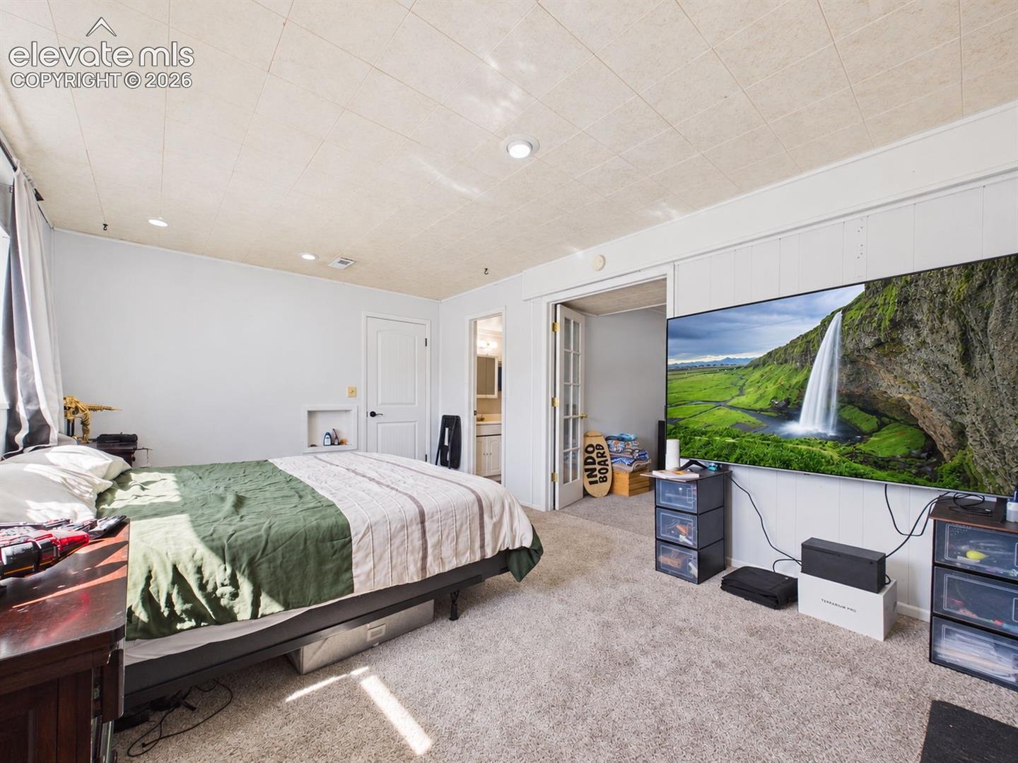 Additional view of the spacious bedroom highlights generous floor space, recessed lighting, and direct access to an adjoining dressing/storage area and bathroom.