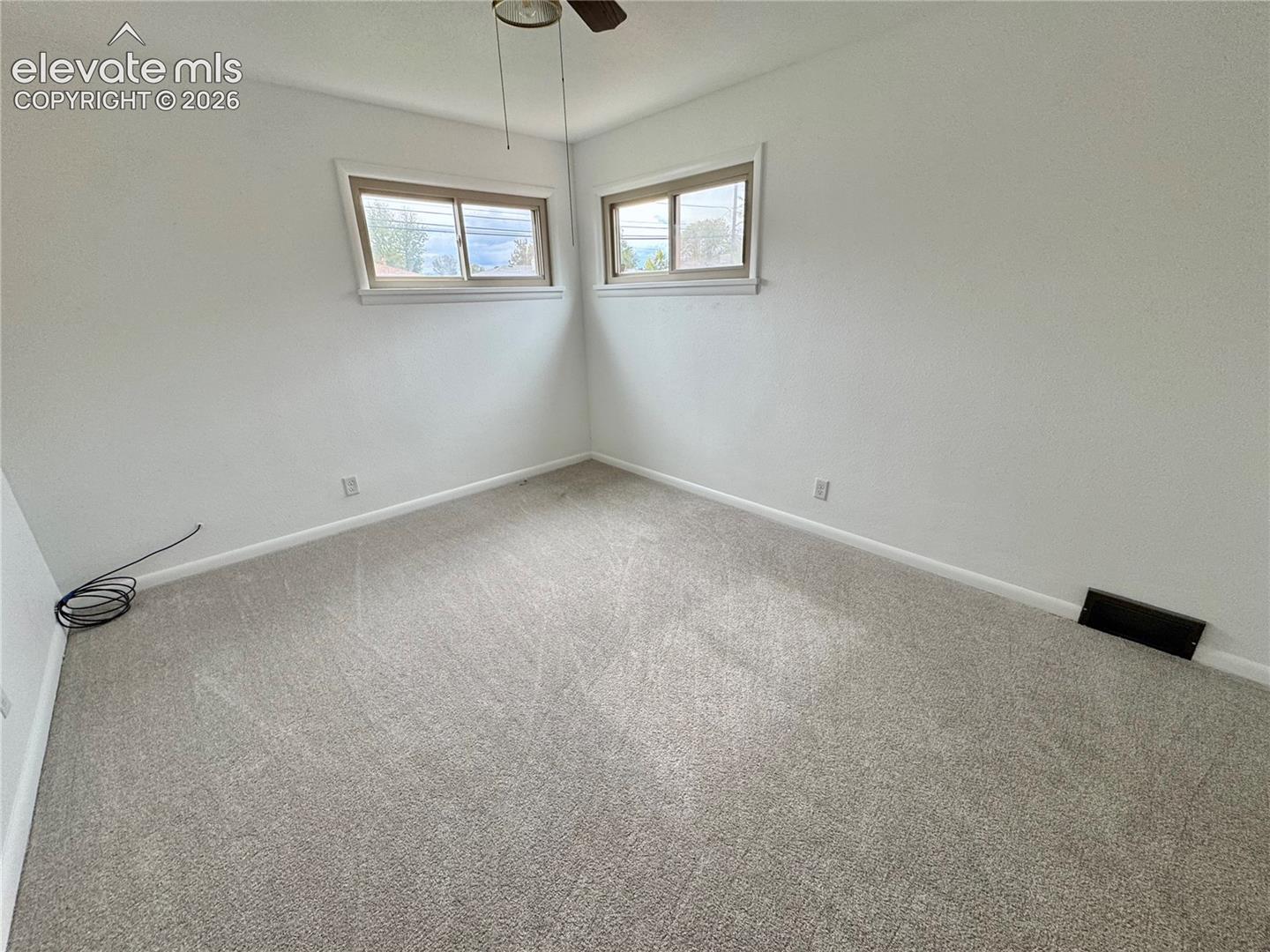 Neutral interior room featuring neutral carpeting, dual sliding windows with trim, and a ceiling-mounted light fixture