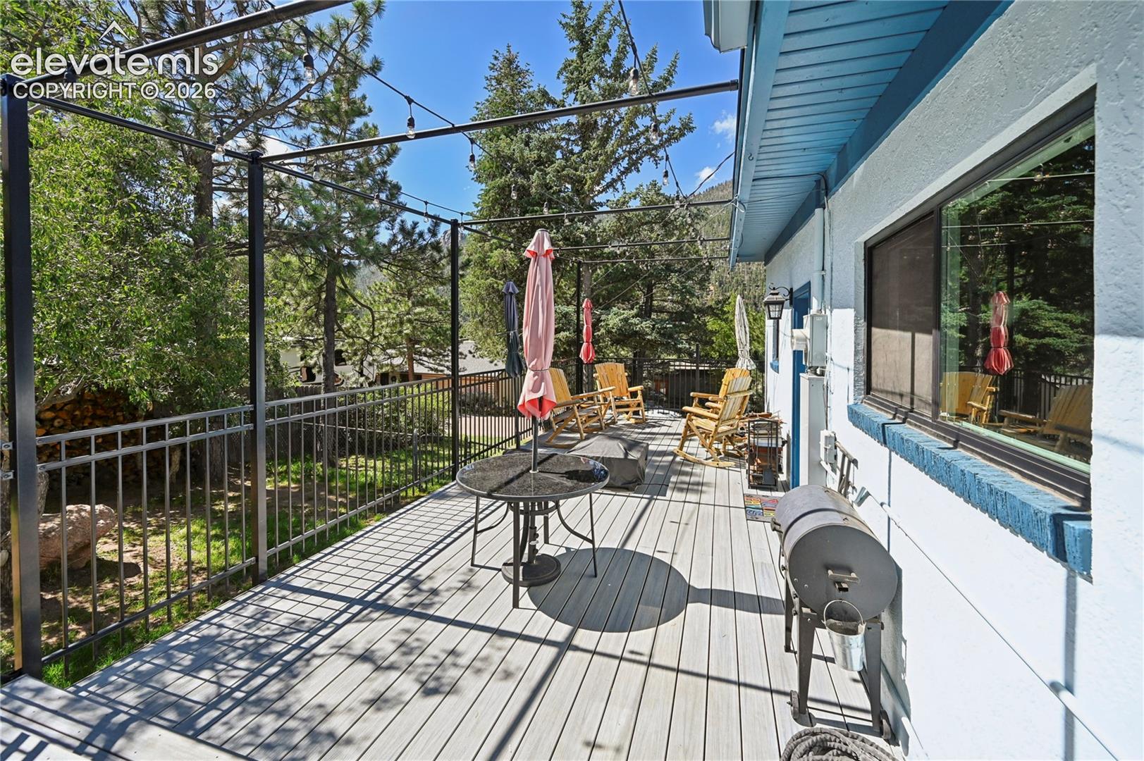 Expansive deck with composite decking, decorative metal railing, string lighting, and a structural pergola