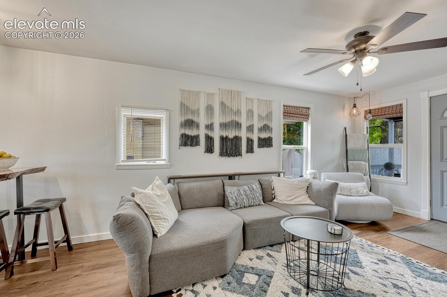 Living area featuring luxury vinyl plank flooring, white walls, and a ceiling fan with integrated lighting