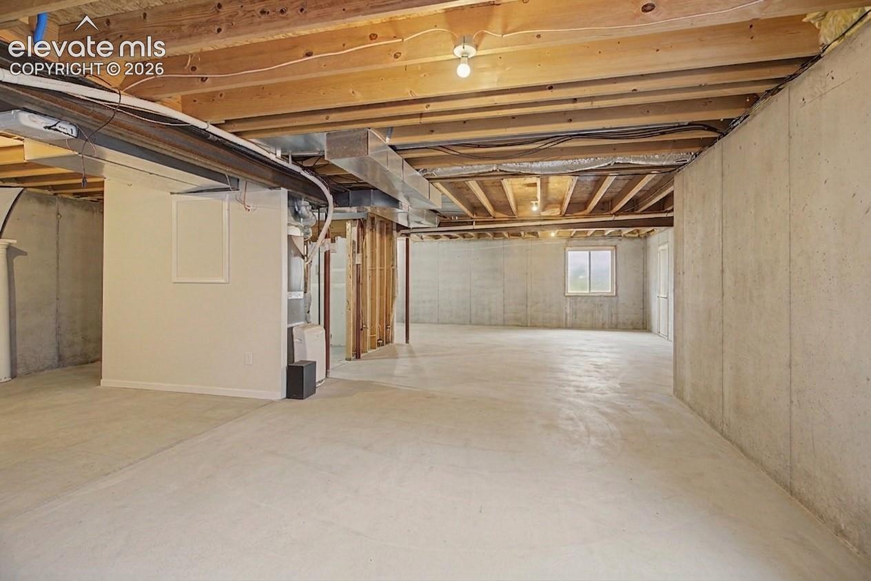 Unfinished basement featuring exposed wood ceiling joists, concrete flooring, and concrete foundation walls
