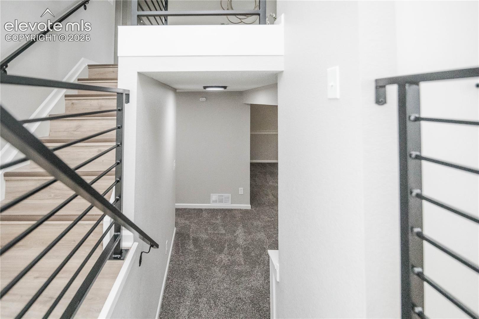 Staircase featuring wood-finish treads and industrial-style matte black horizontal metal railings