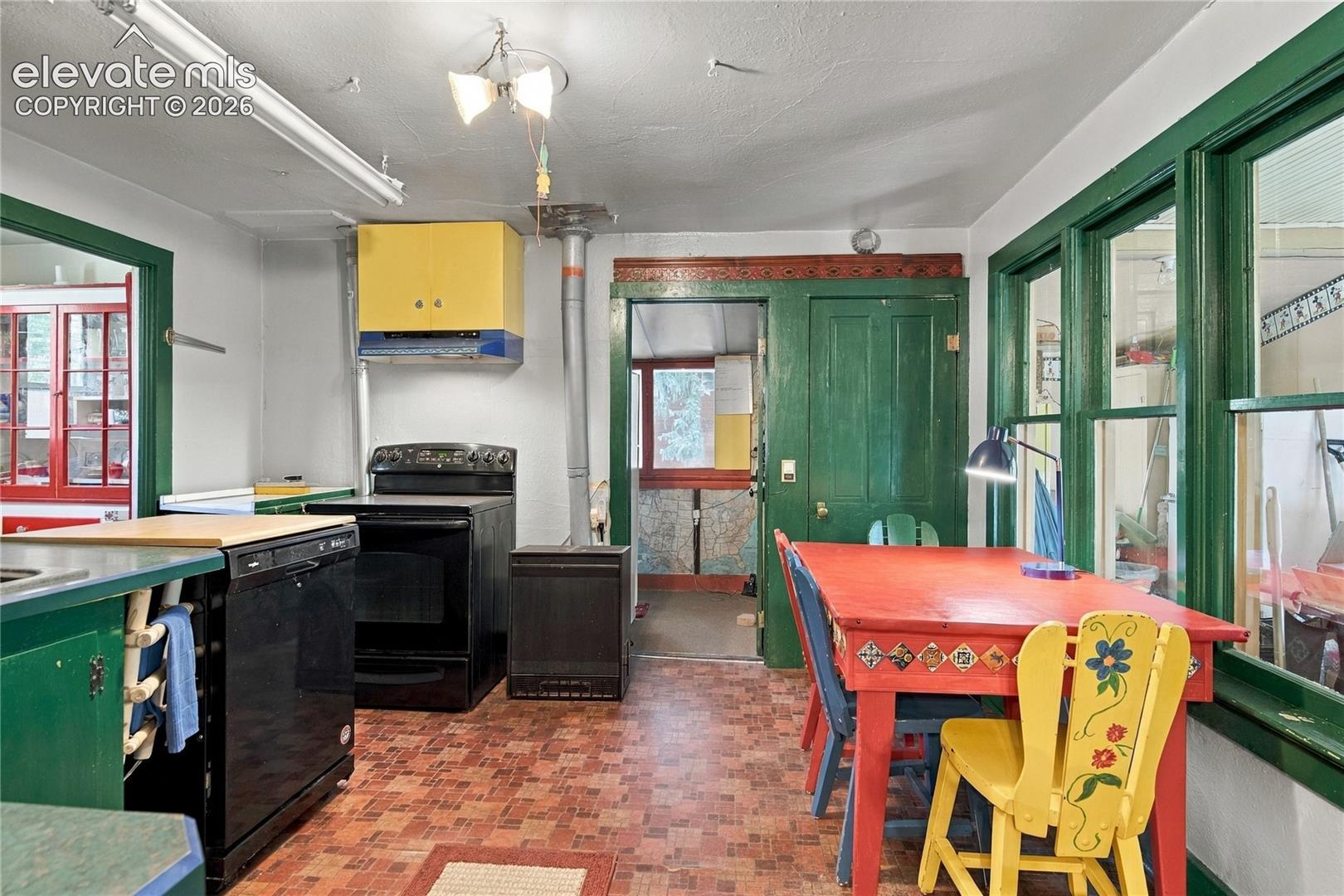 Large kitchen area with a butler's pantry on the left and room for a kitchen table. On the right is an area set up for the fridge and more storage. The green door leads to laundry and a back door. 