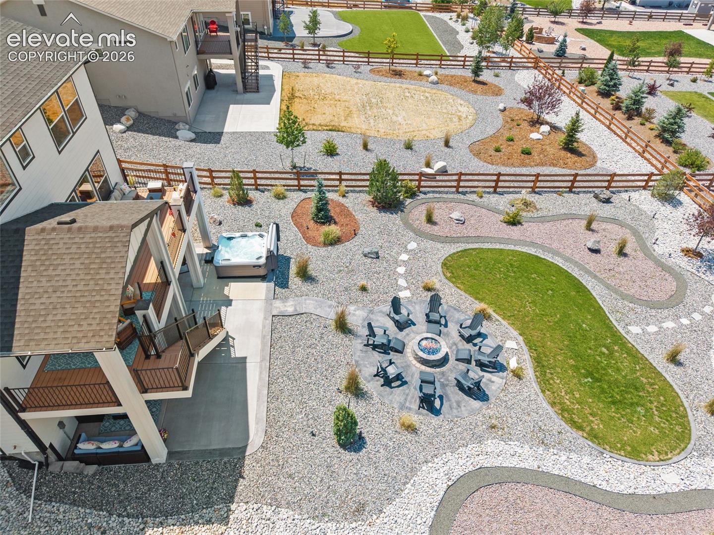 Expansive property featuring a multi-level deck, built-in hot tub, fire pit area, and a large manicured lawn