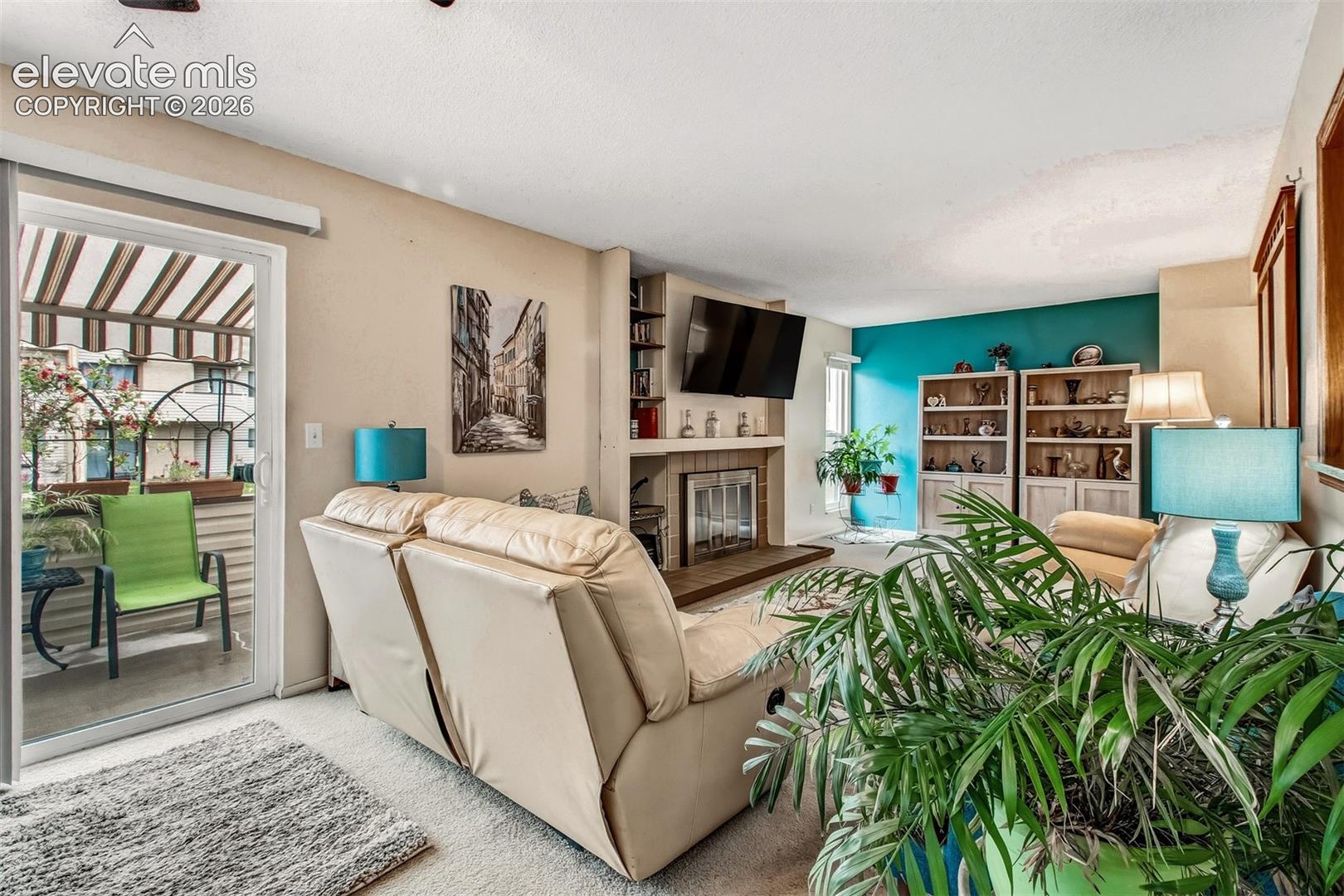 Living area featuring a fireplace with a raised hearth, built-in shelving, and sliding glass door access to a covered patio