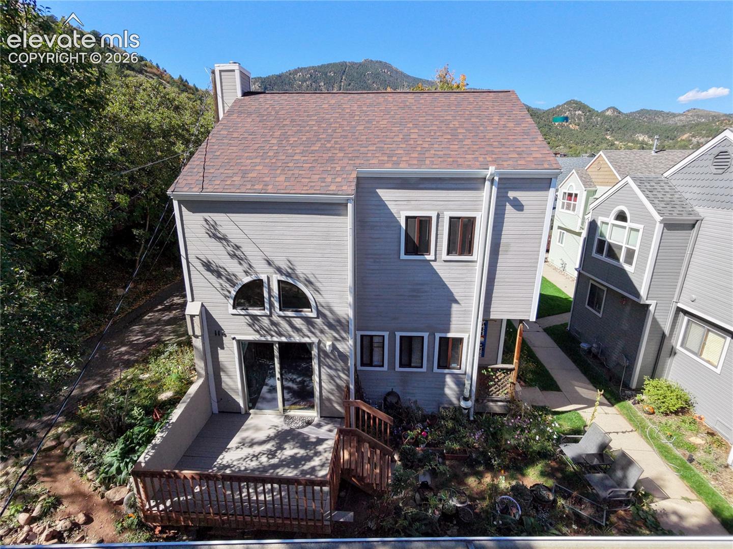 Multi-level exterior with siding, a shingle roof, rear deck, and a patio area