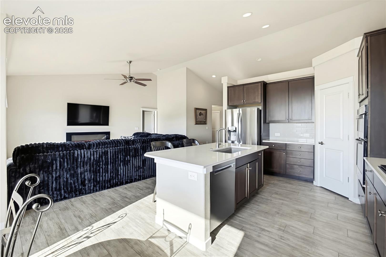 Open-concept kitchen featuring an island with a quartz countertop, stainless steel sink, and stainless steel dishwasher