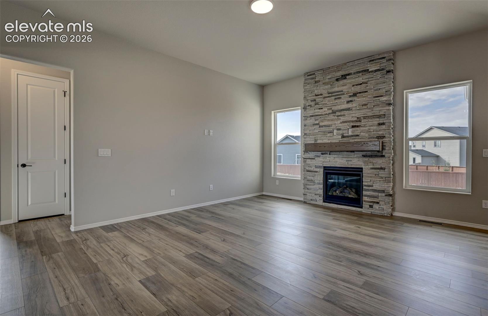 gas fireplace with stacked stone to ceiling and wood mantel