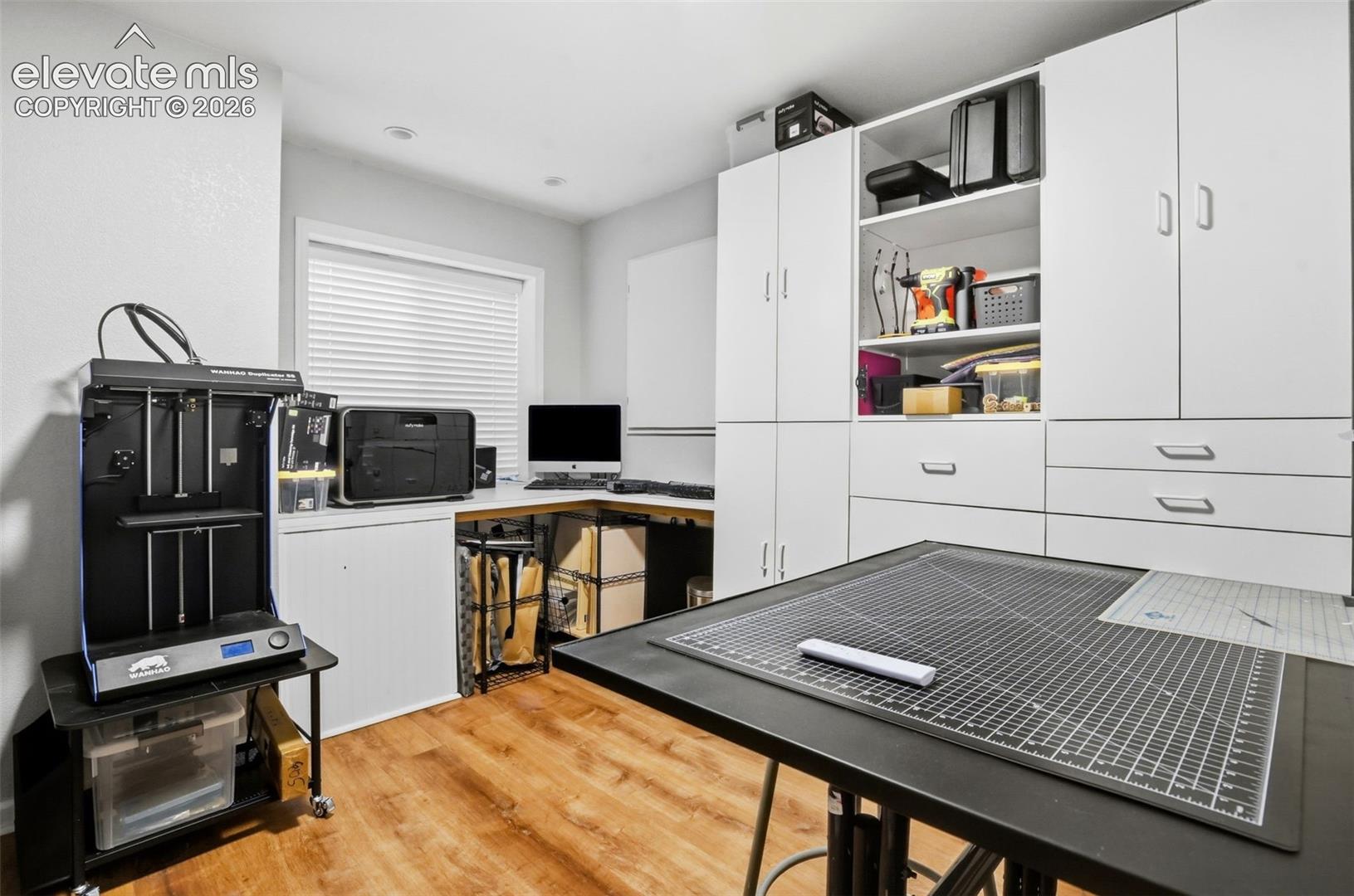 Basement studio/craft room with recessed lighting, newer flooring, and built-in desk and cabinets.