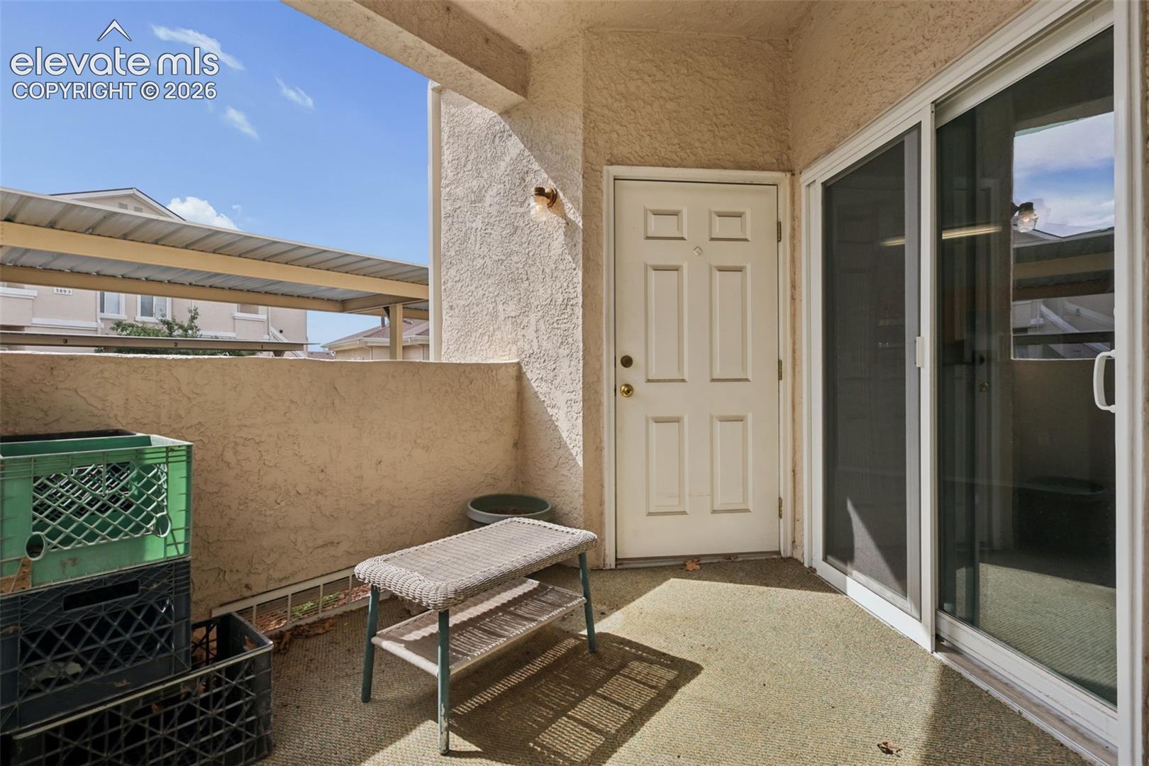 Outdoor patio featuring a stucco exterior, privacy wall, and sliding glass door