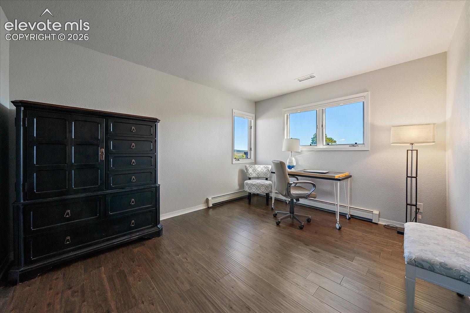 Room featuring wood-finish flooring, neutral wall paint, and multiple horizontal slider windows
