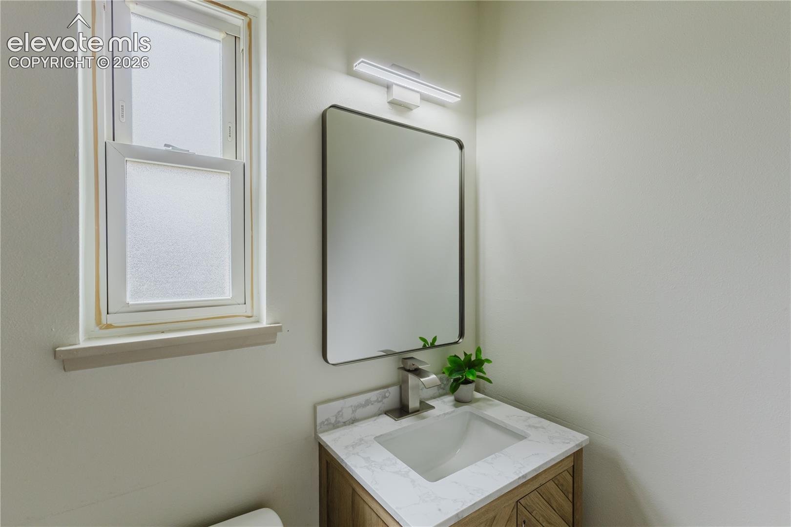 Modern vanity with a rectangular undermount sink, a stone-finish countertop, and a wood-finish cabinet with a herringbone pattern