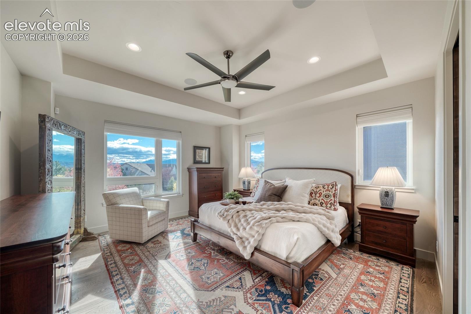 Tray ceiling with recessed lighting, six-blade ceiling fan, and wood-finish flooring