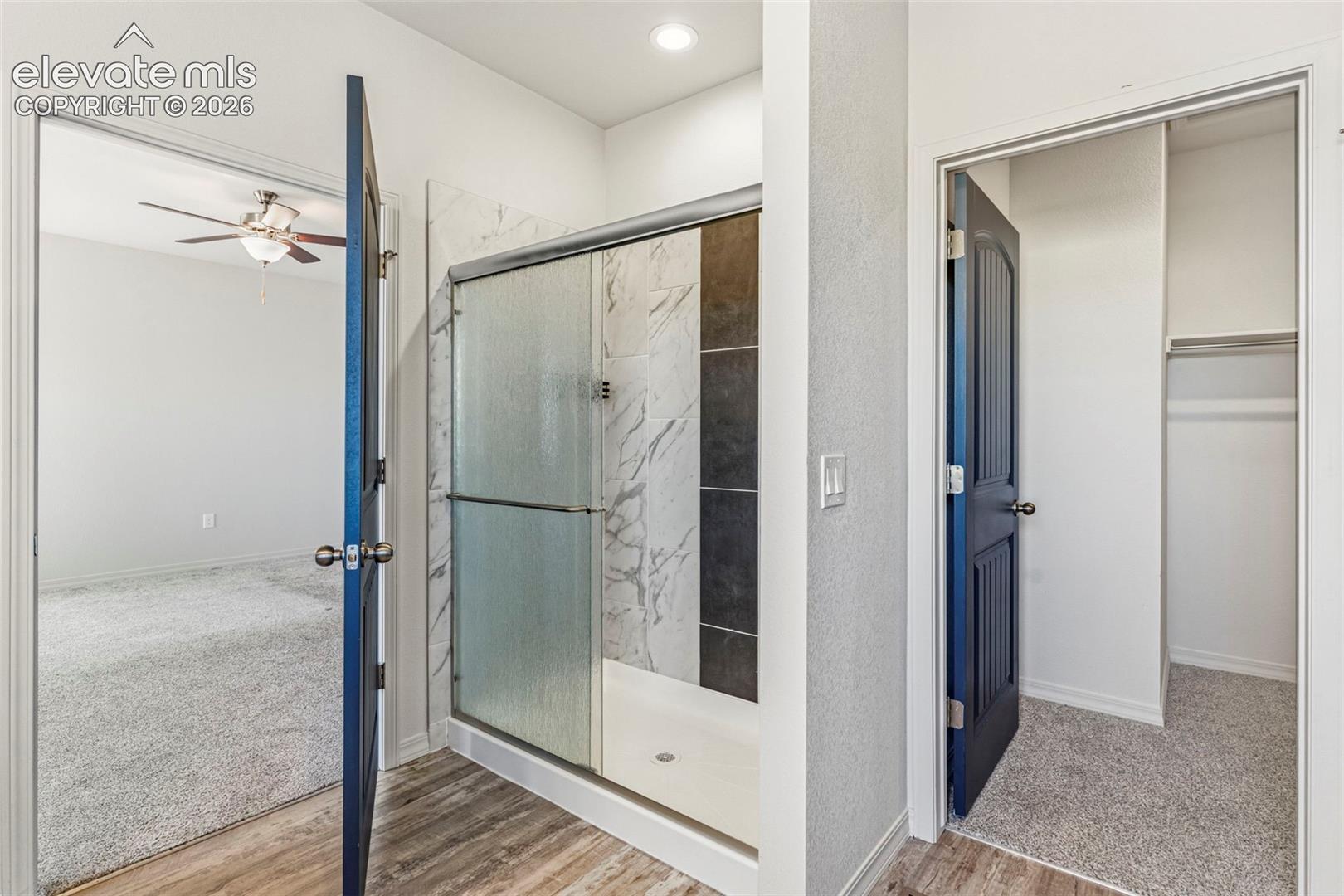 Walk-in shower featuring patterned tile surround and clear glass enclosure
