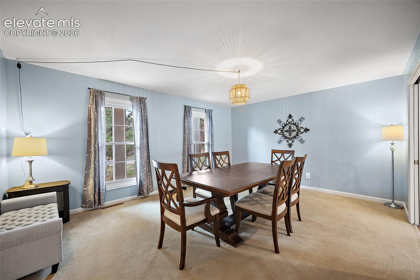 Room featuring wall-to-wall carpeting, three windows with multi-pane glazing, and a tiered drum-style pendant light fixture