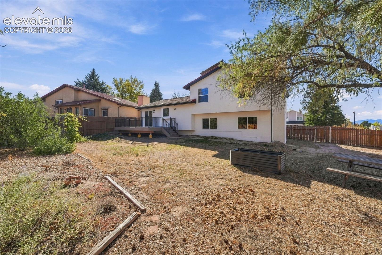 Backyard featuring an elevated wood deck, wood privacy fencing, and mature trees