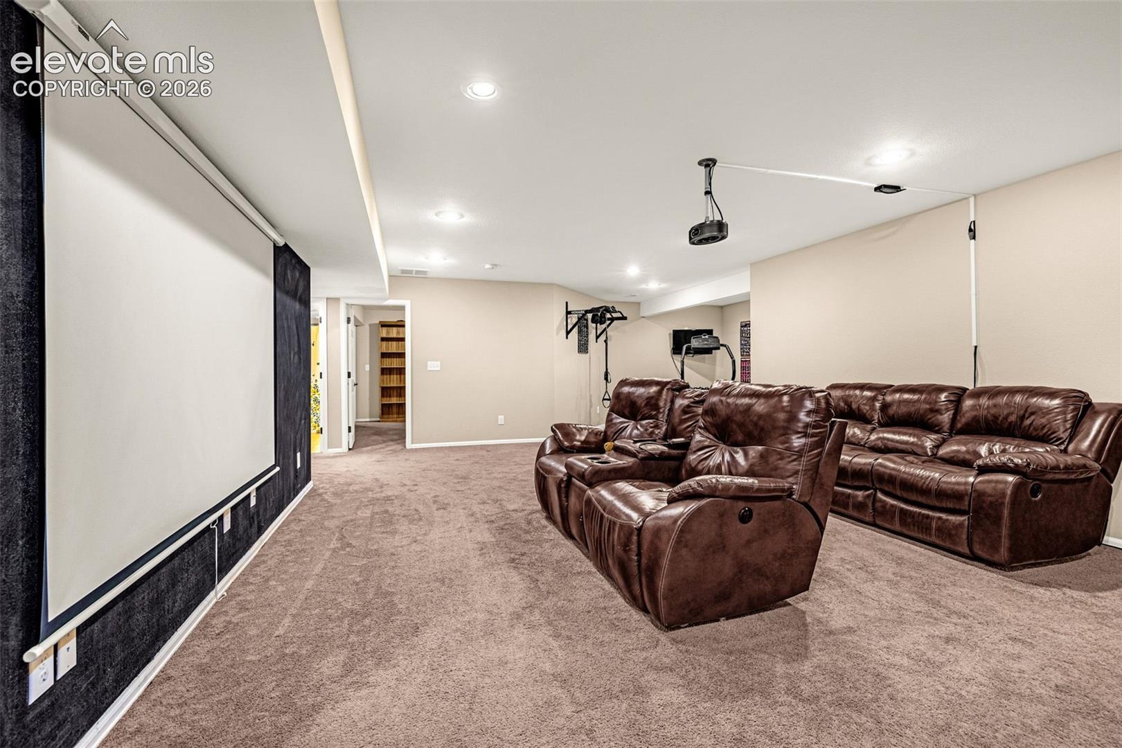 Expansive entertainment room with recessed lighting, integrated projector, and large pull-down screen