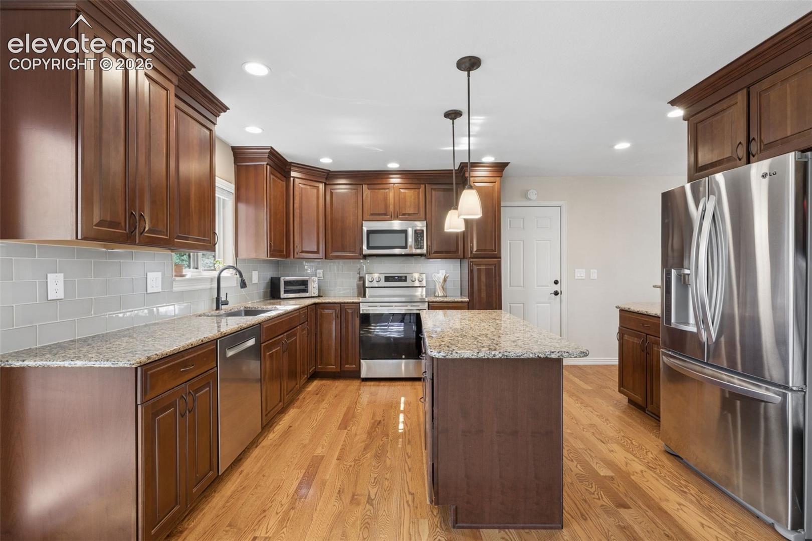 Updated kitchen with island, granite counters and glass subway tile backsplash