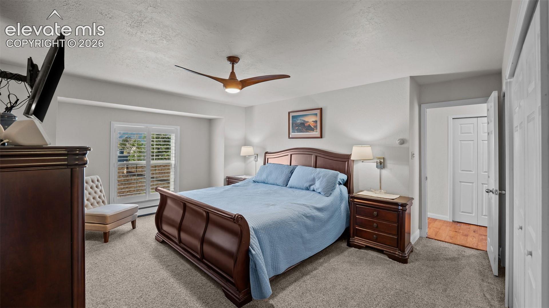 Neutral-toned wall-to-wall carpeting, three-blade ceiling fan with integrated light, window with plantation shutters, and dual-panel interior doors