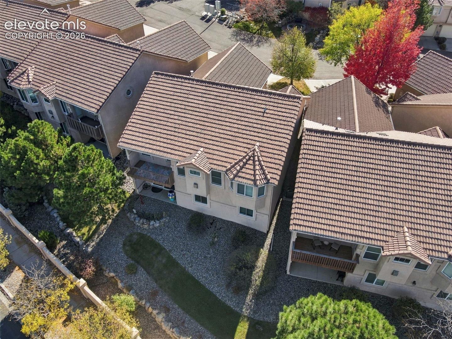 Multi-level exterior featuring a concrete tile roof, stucco siding, and integrated balconies with wood-slat railings