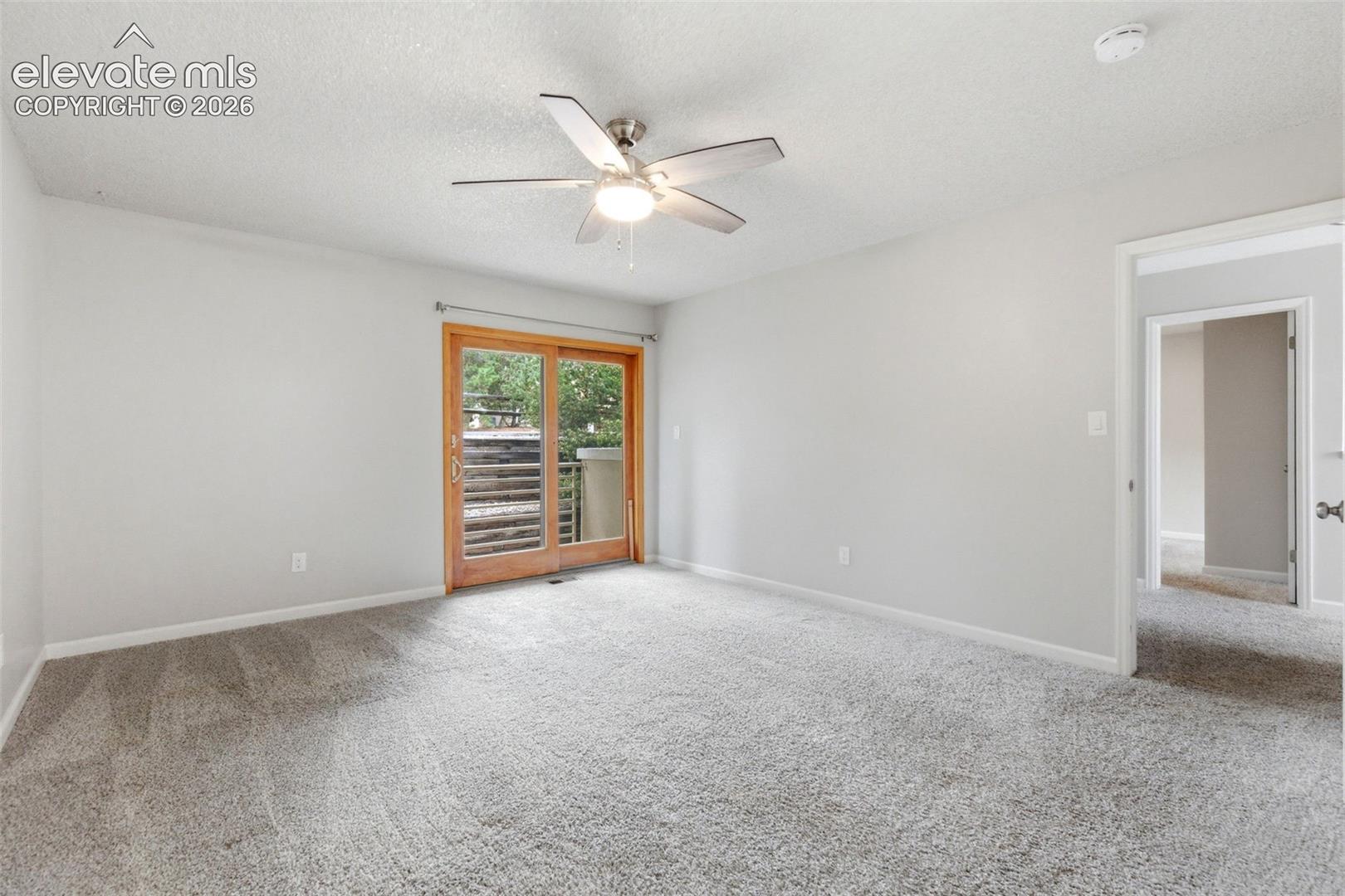 Spacious room featuring light gray carpeting, neutral wall finishes, and a modern ceiling fan with integrated lighting